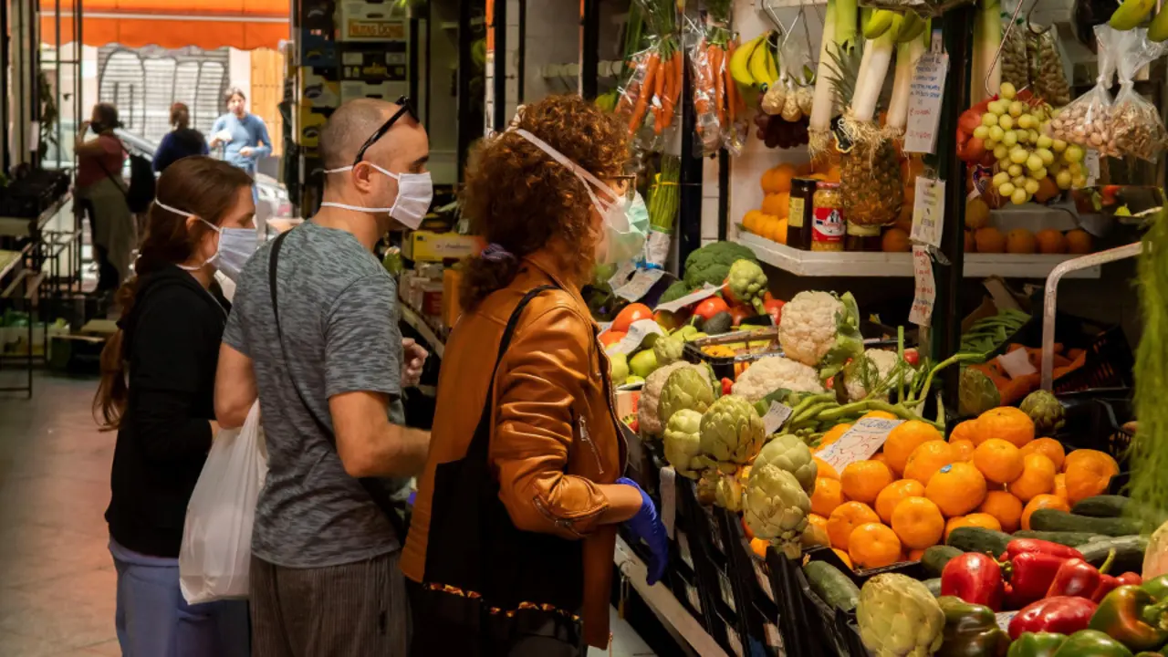 Clientes protegidos con mascarillas haciendo la compra. EFE