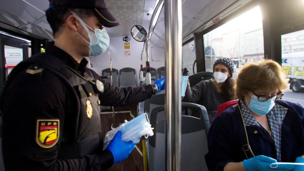 Un axente reparte m&aacute;scaras nun autob&uacute;s urb&aacute;n de Vigo.SALVADOR SAS (Efe)
