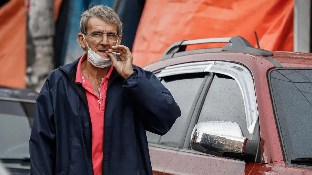 Un hombre fuma con la mascarilla en el cuello. EFE