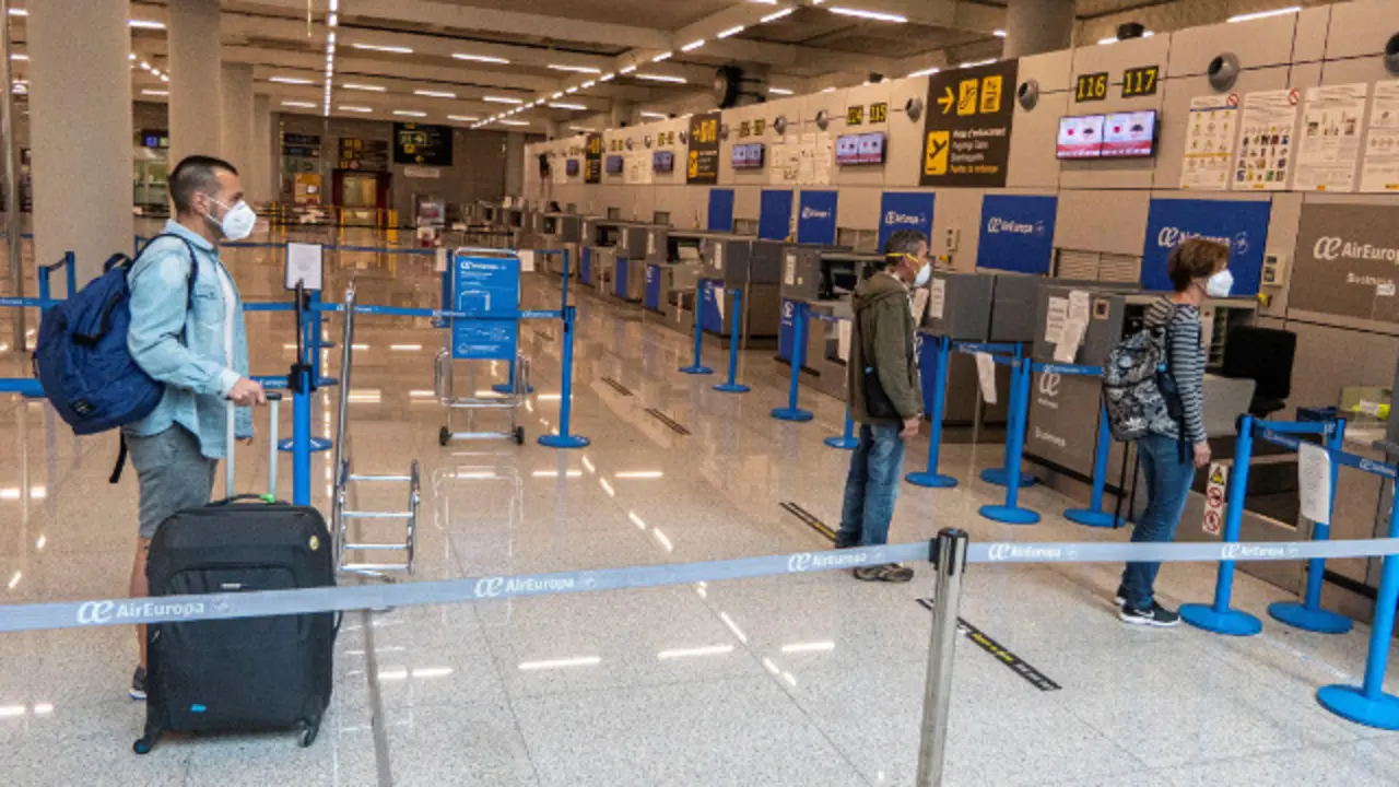 Viaxeiros manteñen a distancia de seguridade antes de facturar a súa equipaxe no interior do Aeroporto de Palma. EFE
