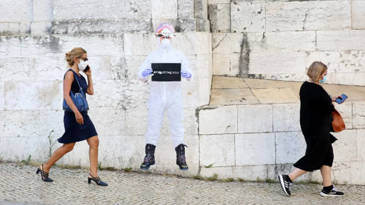 Dos mujeres con mascarilla pasan ante un mural que recomienda quedarse en casa. EP