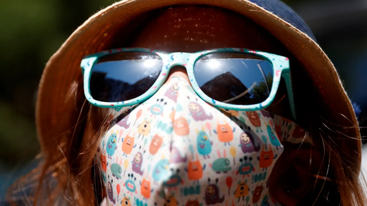 Unha nena con máscara e con chapeu para protexerse da calor. MARISCAL (EFE)