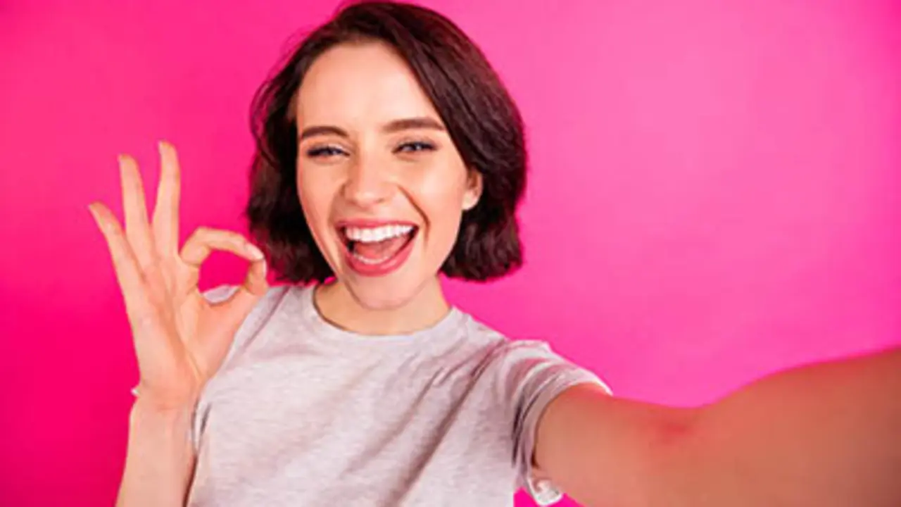 Self portrait of charming, cheerful attractive nice cute girlfriend showing you ok sign taking selfie wearing grey t-shirt assessing joke quality while isolated with fuchsia bright color background