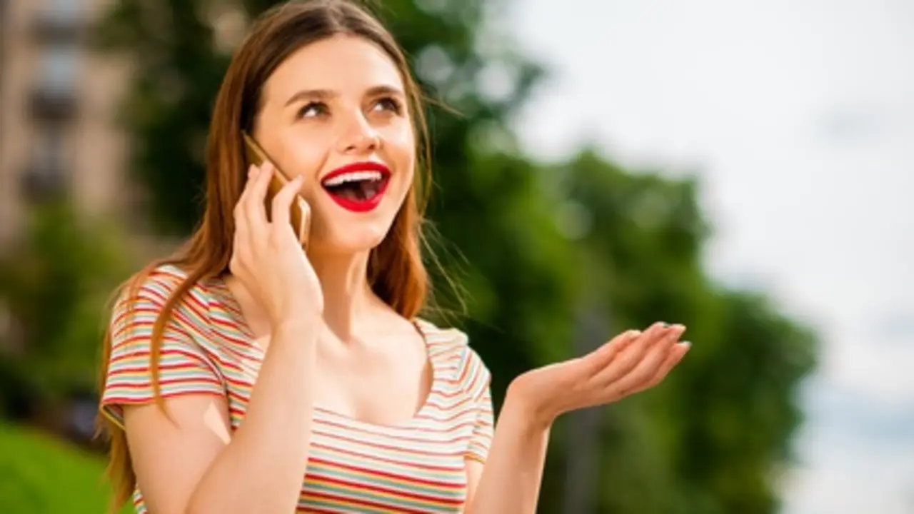 Portrait of charming lady with foxy ginger haircut using modern technology,speaking outdoors