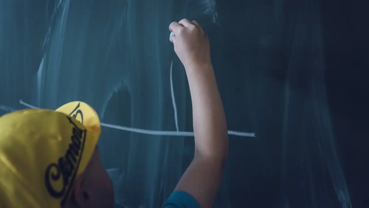 Neno debuxa na pizarra dun aula. PIXABAY