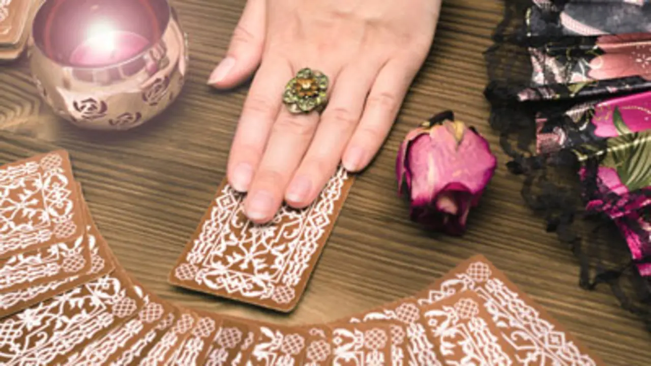 Fortune teller female hands and tarot cards on wooden table. Divination concept. 