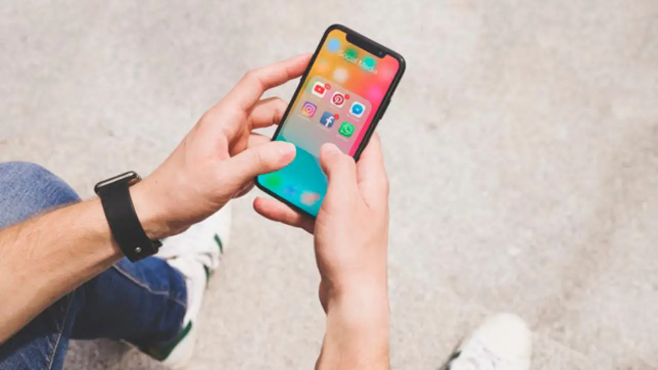 vista-aerea-mano-hombre-usando-aplicacion-medios-sociales-movil_23-2147844468