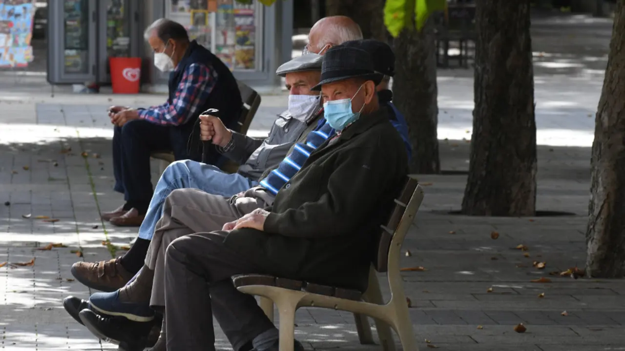 Varias personas con mascarilla en un banco. EFE