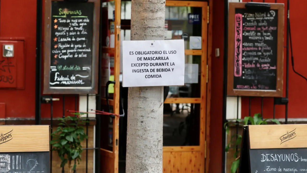Cartel recordando el uso obligatorio de mascarilla en una terraza. efe