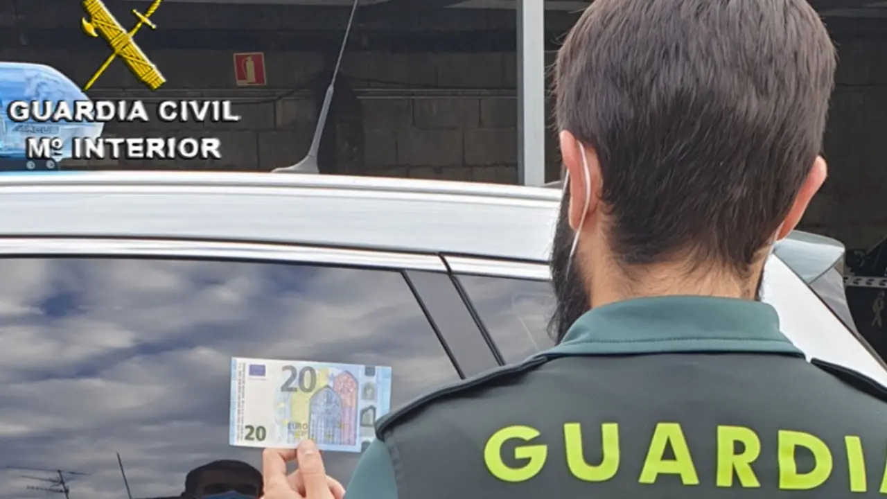 Agente sosteniendo uno de los billetes falsos. EFE