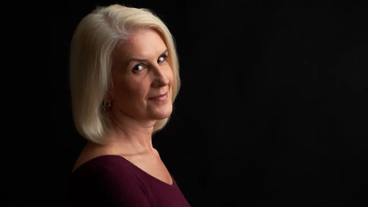 Old blonde woman smiling isolated on black studio background
