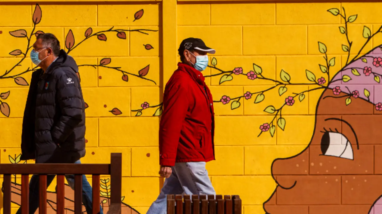 Dous homes camiñan con máscaras nas Pontes. EP