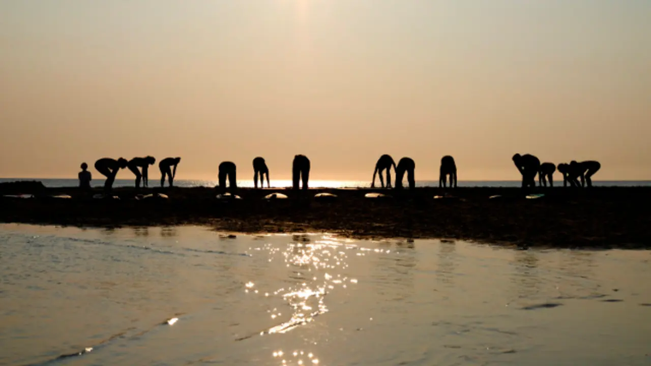 Unos surfistas hacen ejercicios al atardecer en la orilla de la playa de Emelle de Ferrol. Kiko Delgado (EFE)
