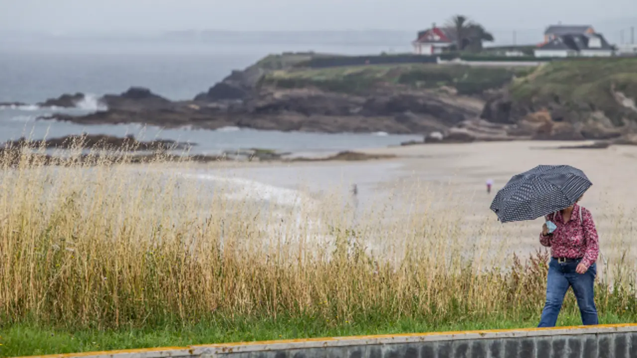 Unha turista pasea por unha praia de Foz nun día de verán con mal tempo. JM ALVEZ