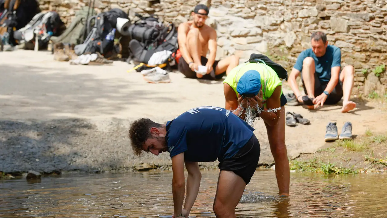 Los peregrinos descansan en un río en Ribadiso, Arzúa, para escapar de la ola de calor. EFE/ LAVANDEIRA JR
