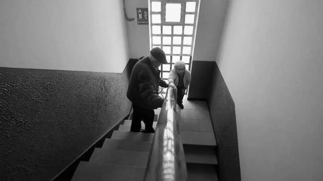 Dúas persoas maiores baixan a escaleira da casa.AEP