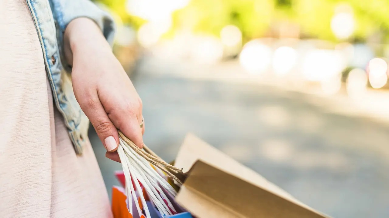 Una mujer sostiene unas bolsas. FREEPIK