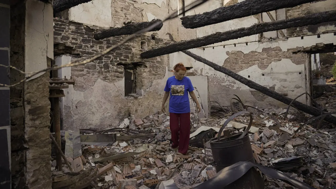 Una mujer observa su casa destruida por el incendio de Larouco. ADRIÁN IRAGO (EUROPA PRESS)