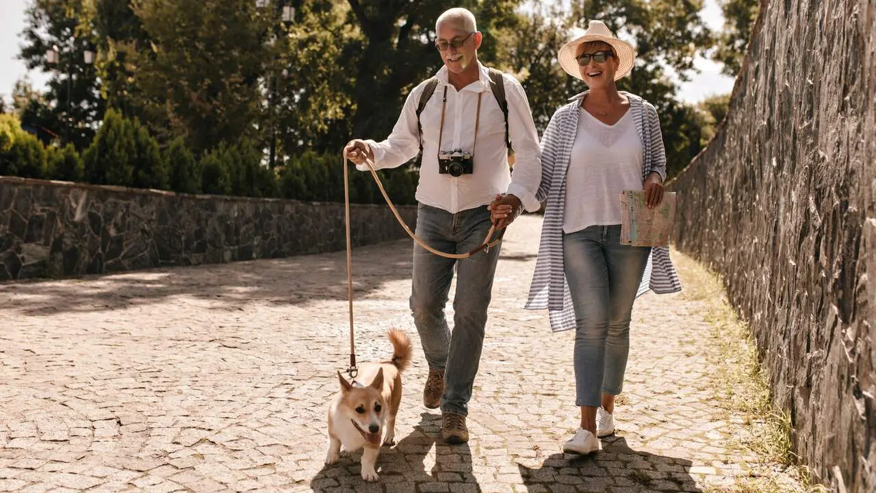 Una pareja de viajeros paseando con su perro. FREEPIK