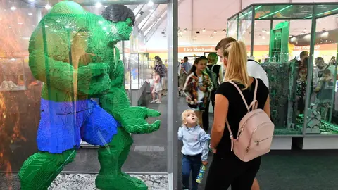 Unha familia diante dun superheroe feito con pezas de Lego. EFE