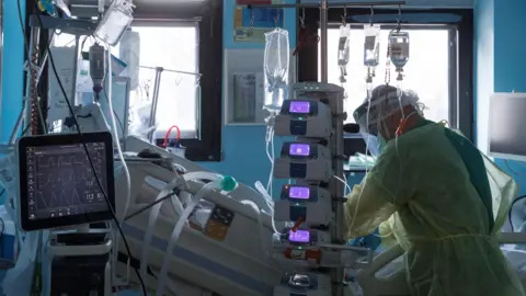 Un enfermero del centro hospitalario atiende a un paciente ingresado por COVID-19 en la UCI. MARCIAL GUILL&Eacute;N (EFE)