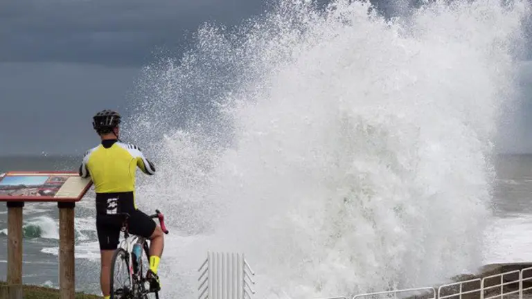 Un ciclista observa el oleaje en Ribadeo. ELISEO TRIGO