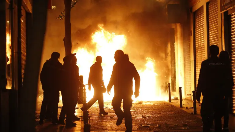 Contenedores incendiados en la calle Mesón de Paredes con la calle del Oso, en el barrio de Lavapiés. JAVIER LIZÓN (EFE)