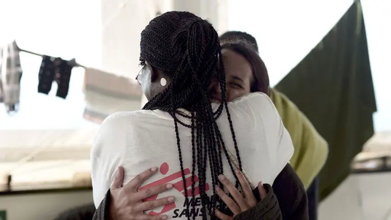 Una de las personas que viajaban en el Aquarius se abraza con un miembro de Médicos sin Fronteras. MSF
