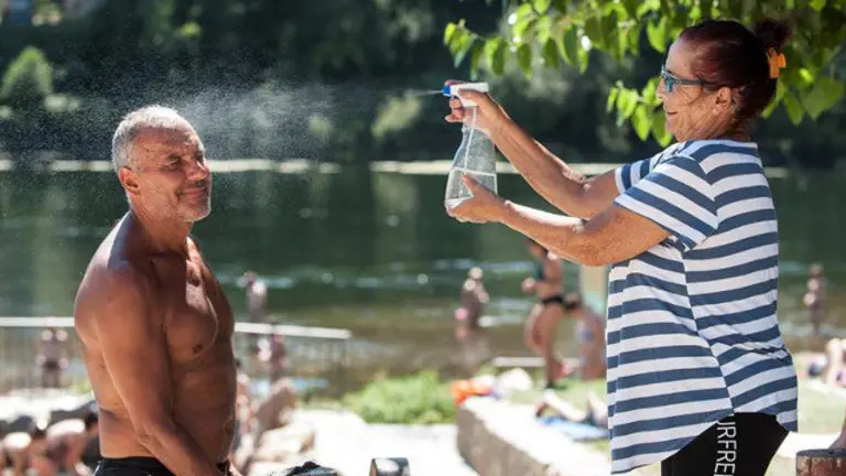 Una mujer refresca a un hombre en las termas de A Chavasqueira, en Ourense. BRAIS LORENZO