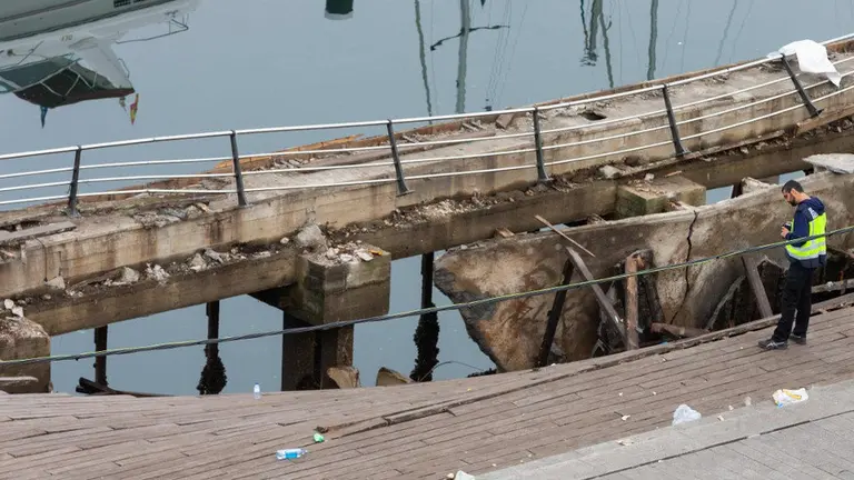Un técnico de la Policía Nacional estudia qué pudo fallar en un paseo a simple vista muy deteriorado. TWITTER (pasarela de O Marisquiño)