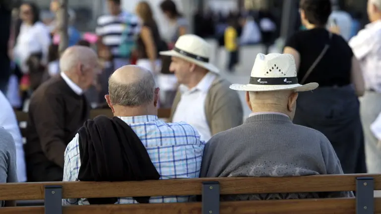 Varios hombres sentados en un banco. AEP