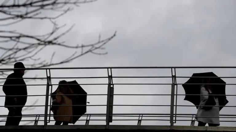 Varias personas se protegen del agua y del viento. LUIS TEJIDO