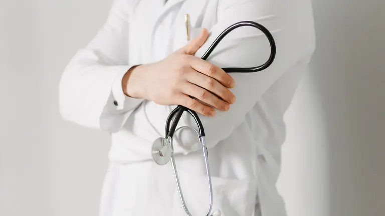 Portrait of a friendly doctor. Isolated on gray