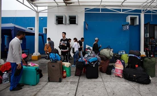 Venezolanos toman un refrigerio a la espera de cruzar el paso fronterizo entre Ecuador y Perú. EFE
