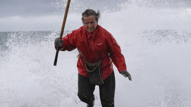 La percebeira Elvira, de 63 años, escapa de la ola mientras faena los percebes en el cabo Roncudo. LAVANDEIRA JR.
