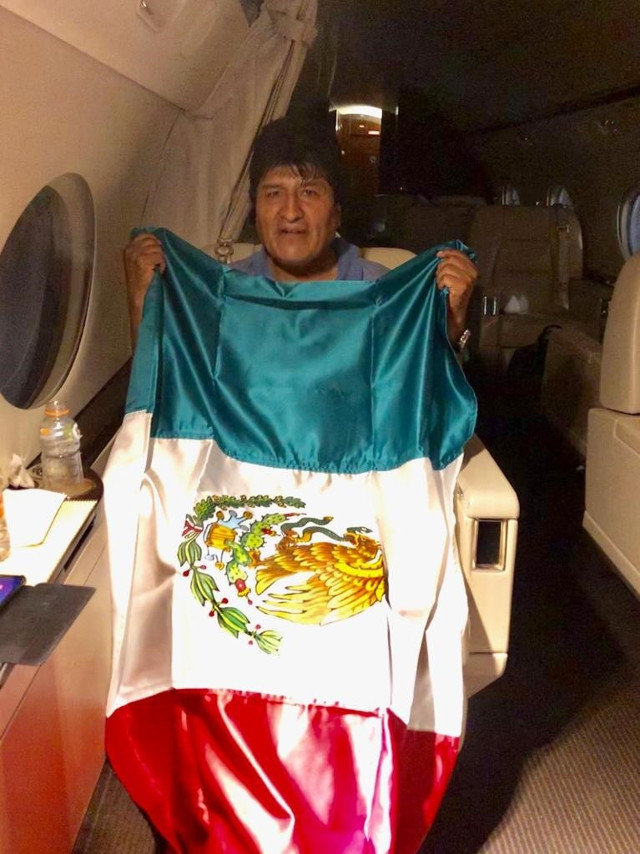 Morales mientras posa con una bandera mexicana, durante su viaje en avión. EFE