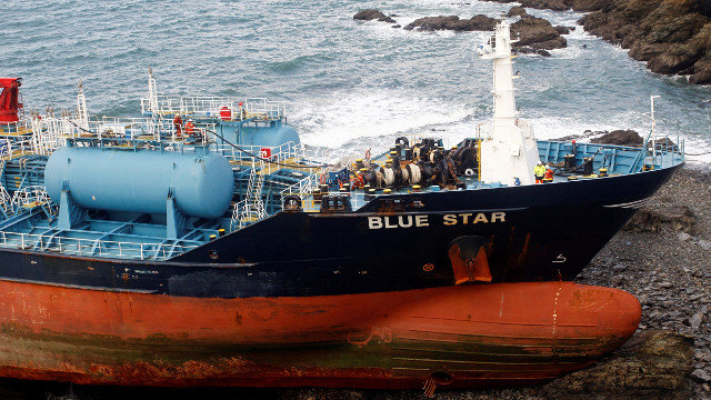 Trabajos de bombeo a tierra del combustible almacenado en el Blue Star. KIKO DELGADO (EFE)