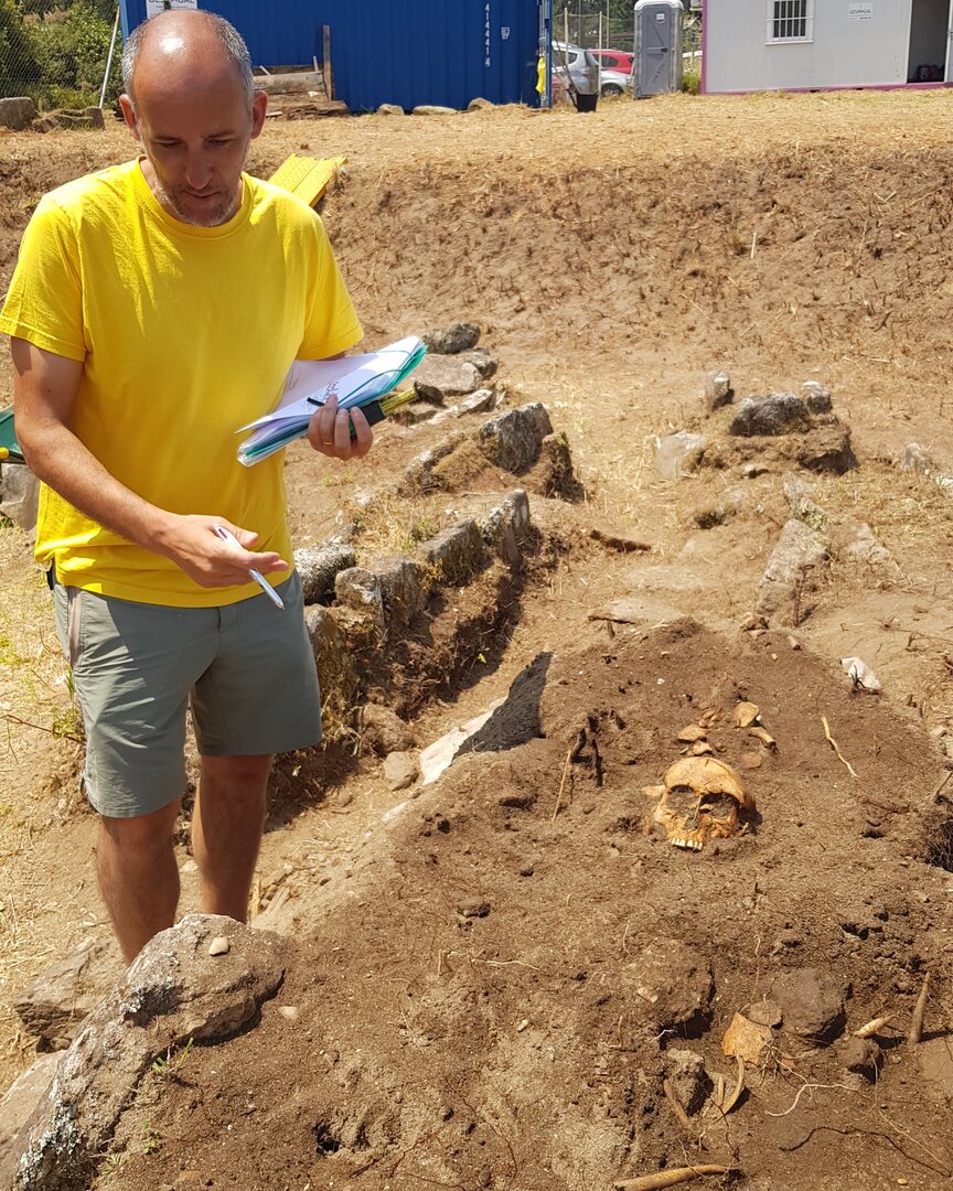 Adolfo trabajando en el yacimiento junto a una calavera. CEDIDA